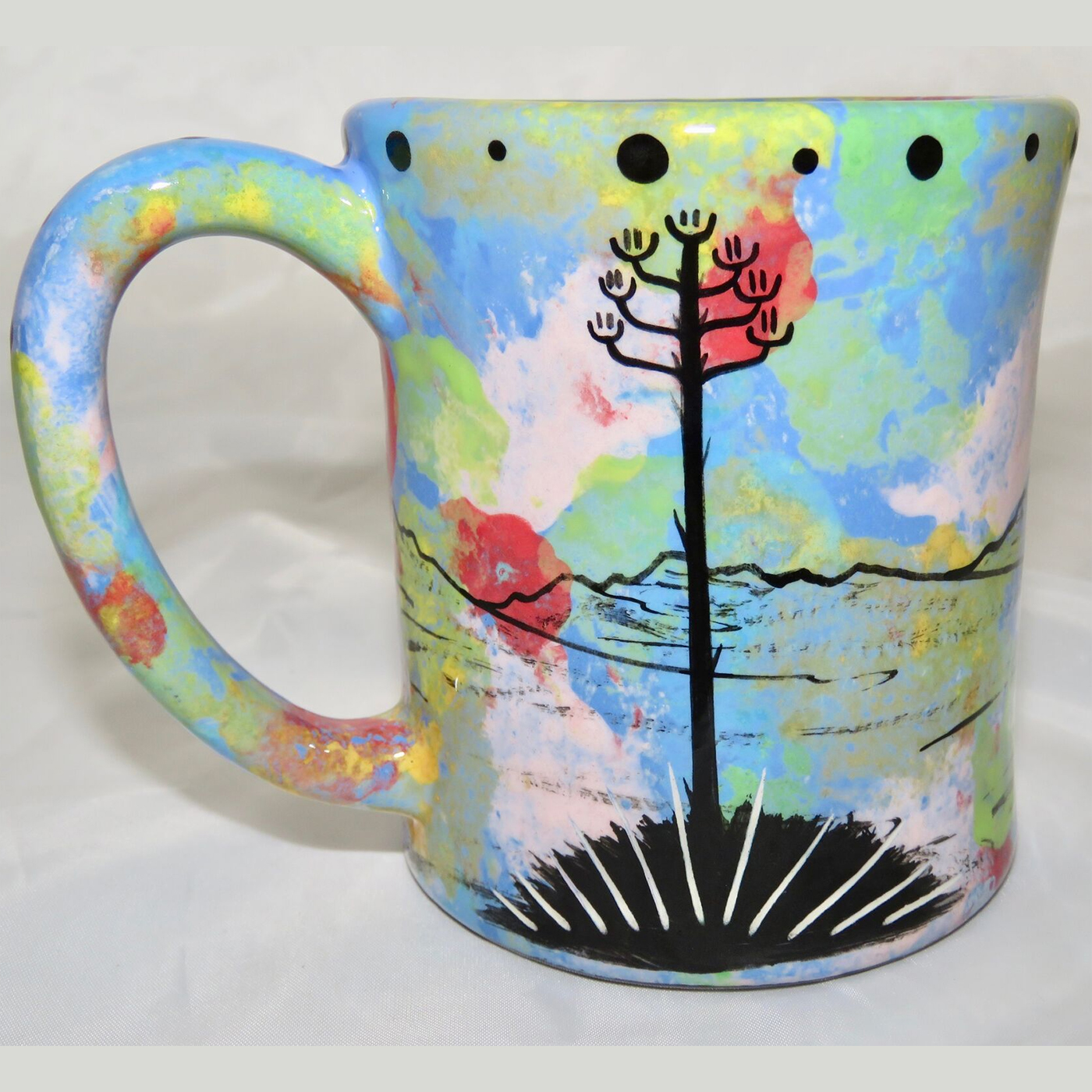 Ear handle mug, howling coyote, blue background. This is the reverse side showing Aravaipa vegetation.