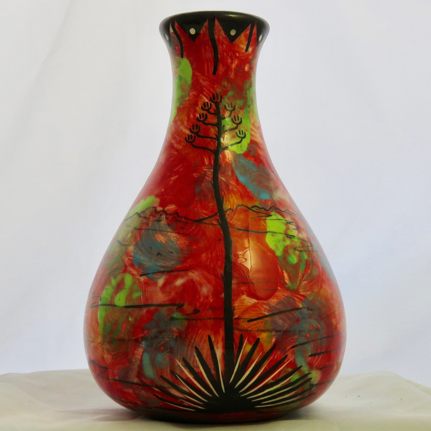 Mana Pottery Teardrop Vase with jumping deer on one side and native Aravaipa desert vegetation on reverse, on a background of crimson.