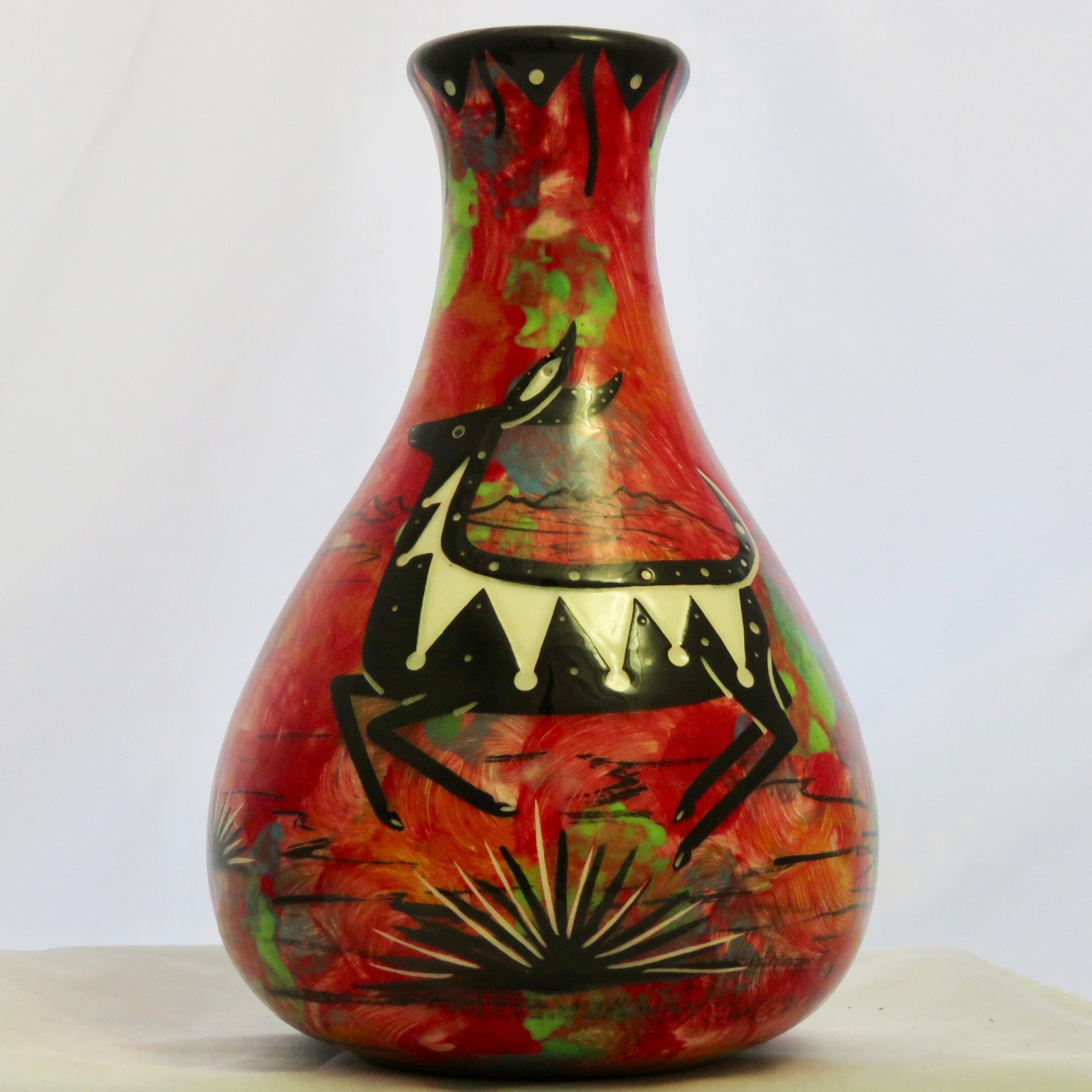 Mana Pottery Teardrop Vase with jumping deer on one side and native Aravaipa desert vegetation on reverse, on a background of crimson.