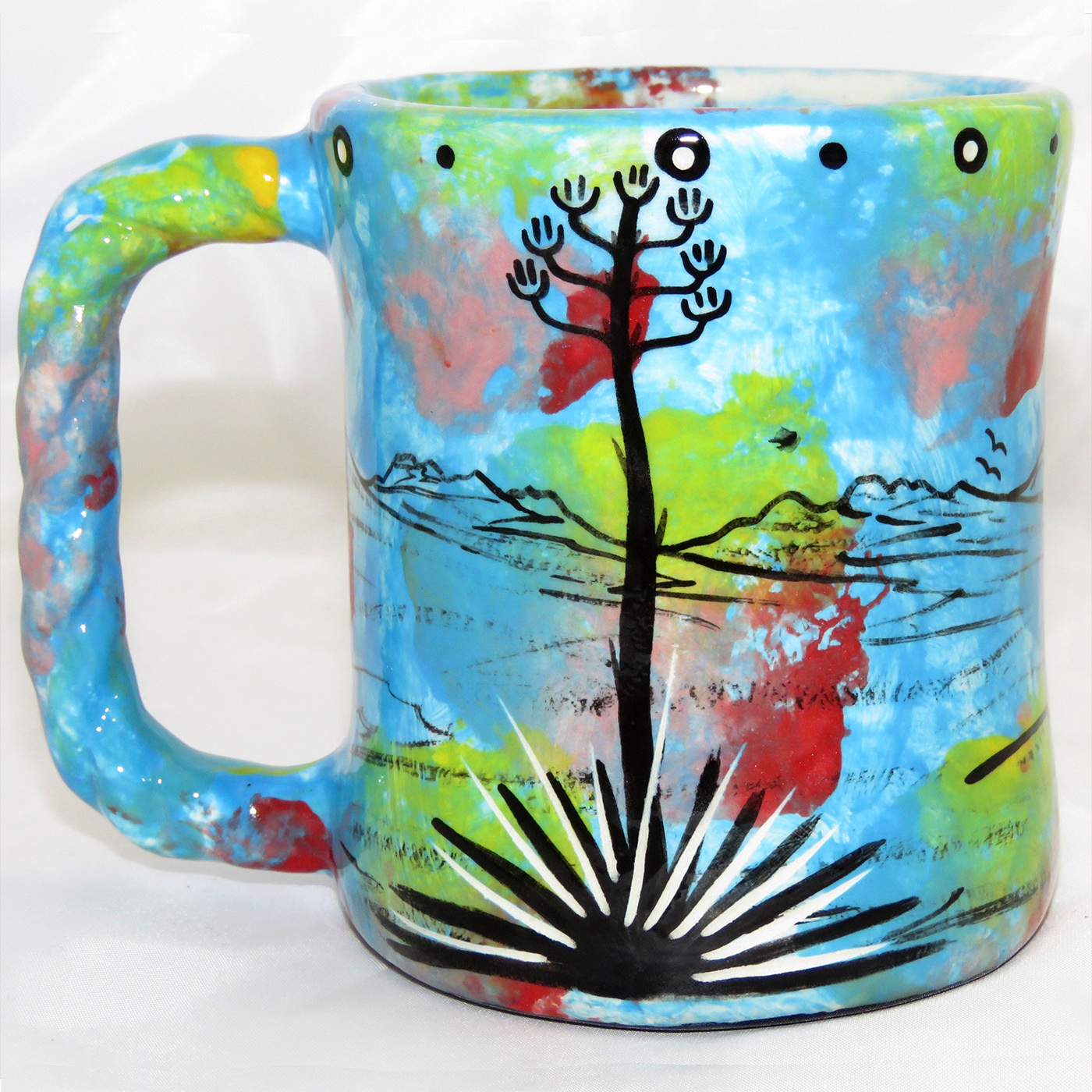 Mana Pottery rope mug featuring deer on on one side and native Aravaipa vegetation on reverse, on turquoise blue background. The "rope" mug has a handle that is shaped like rope.