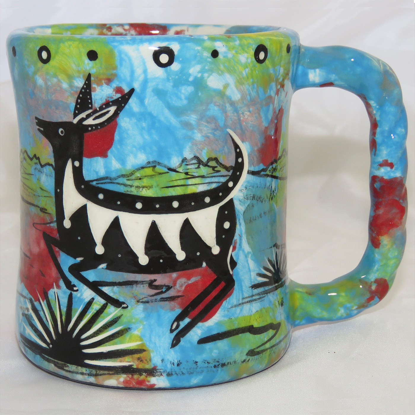 Mana Pottery rope mug featuring deer on on one side and native Aravaipa vegetation on reverse, on turquoise blue background. The "rope" mug has a handle that is shaped like rope.