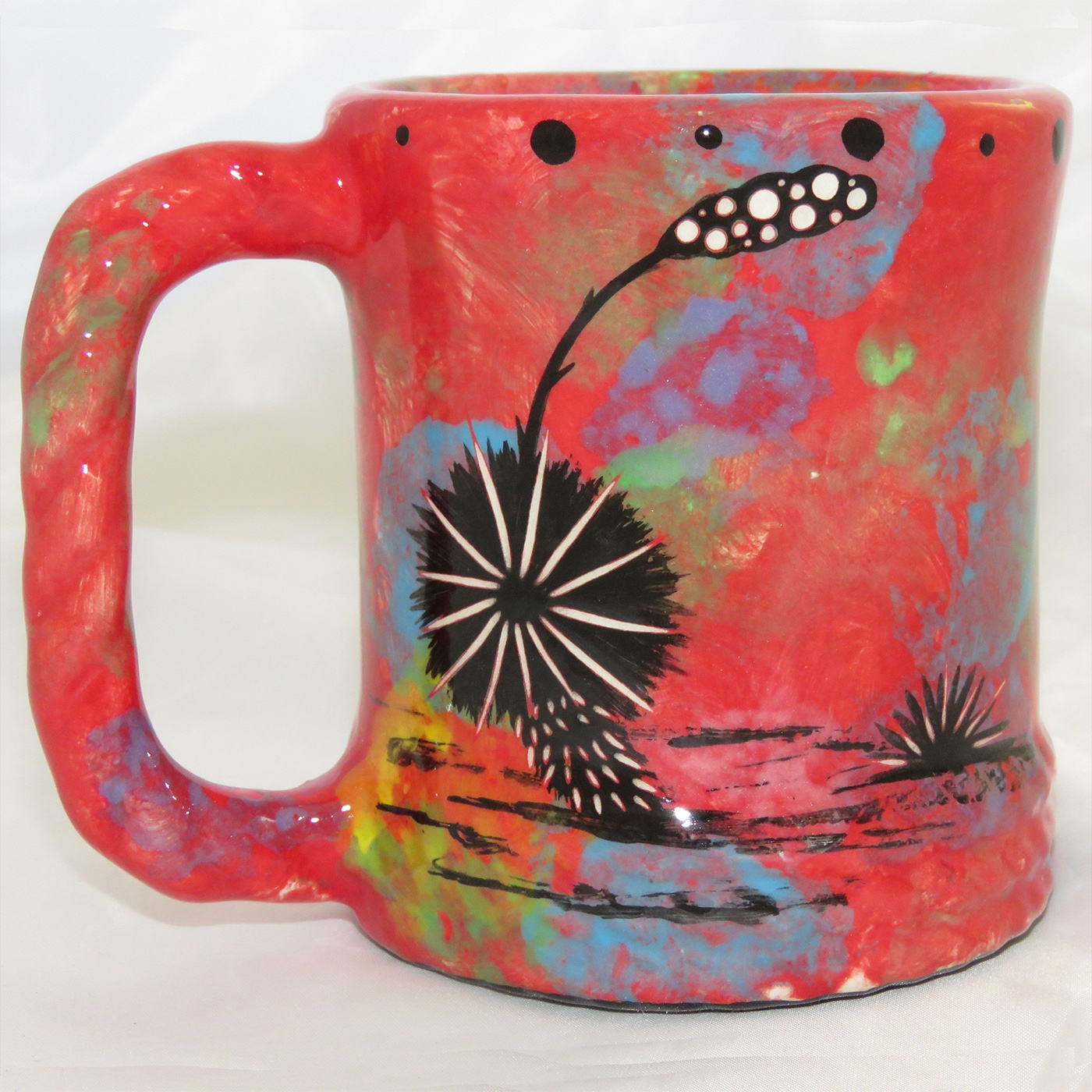 Mana Pottery rope mug featuring hummingbird with spread wings on one side and native Aravaipa vegetation on reverse, on crimson background. The "rope" mug has a handle that is shaped like rope.