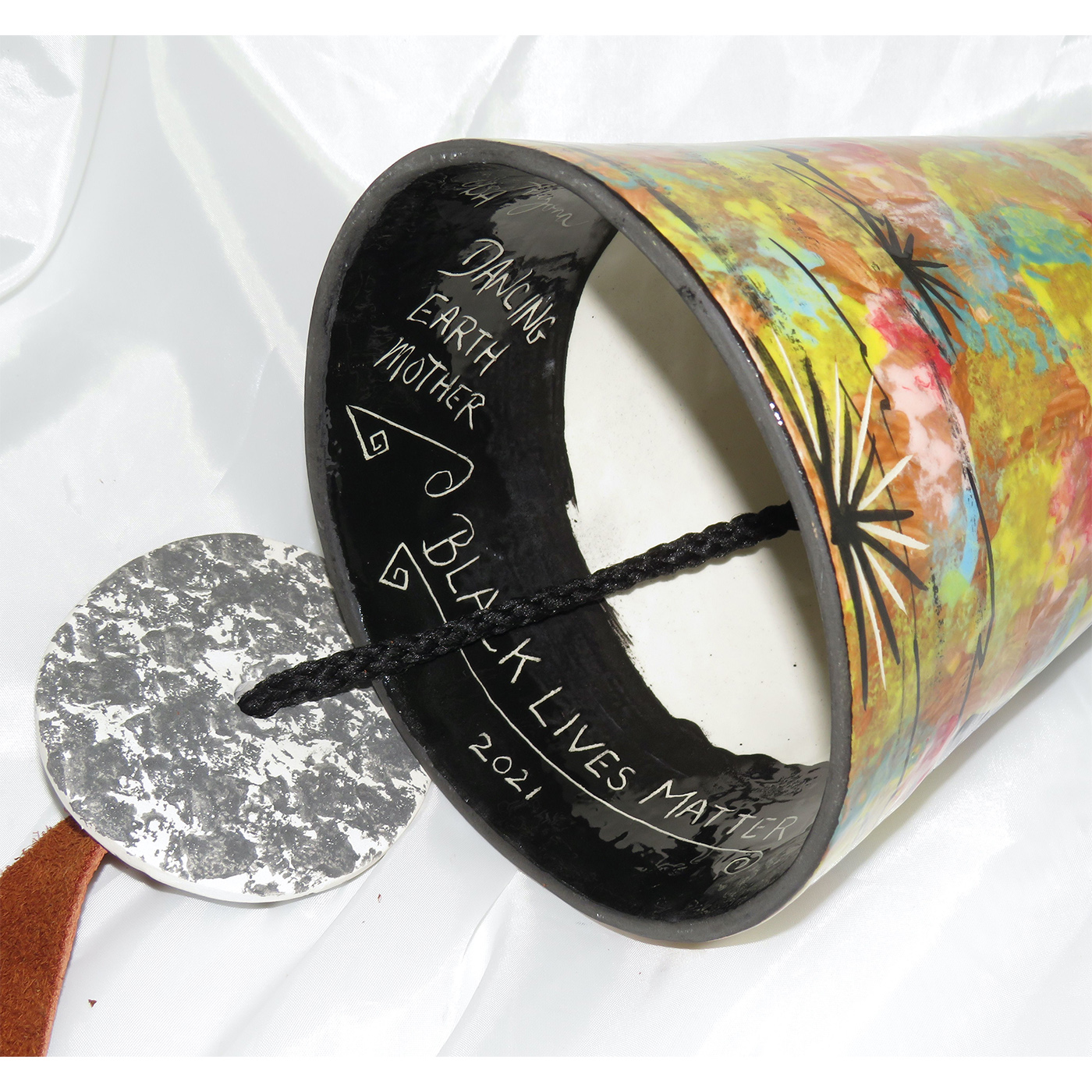 Interior of Mana Pottery large wind bell featuring dancing Earth Mother and desert landscape on reverse sides on a golden brown background.