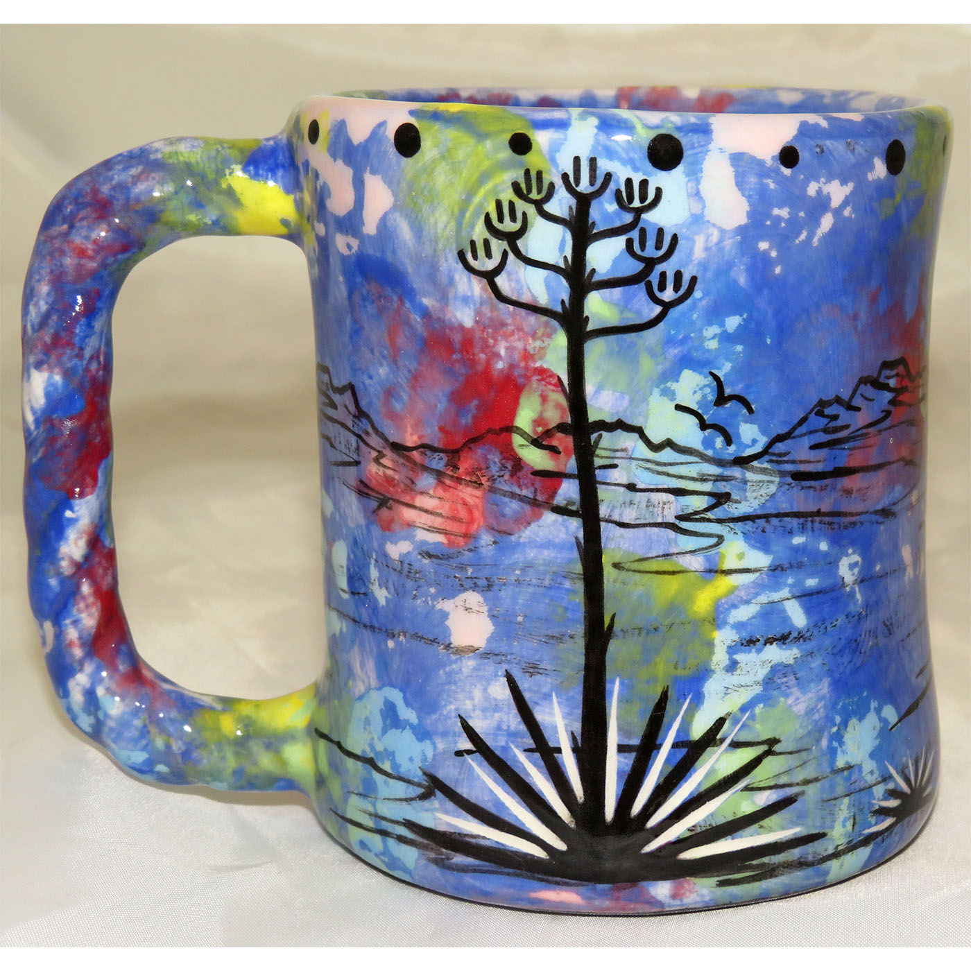 Mana Pottery rope mug featuring running deer and desert landscape on reverse sides, on blue background.