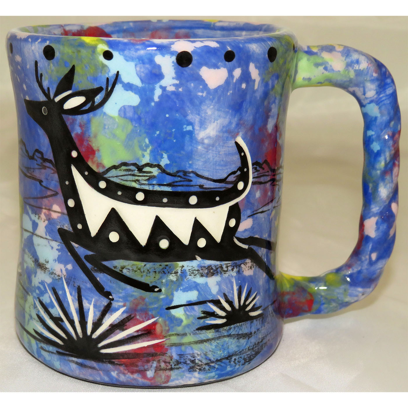 Mana Pottery rope mug featuring running deer and desert landscape on reverse sides, on blue background.