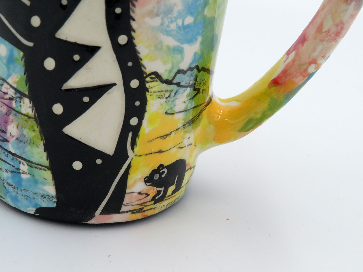 Baby detail on Mana Pottery large mug featuring mama bear with baby and desert landscape on reverse, on confetti background.