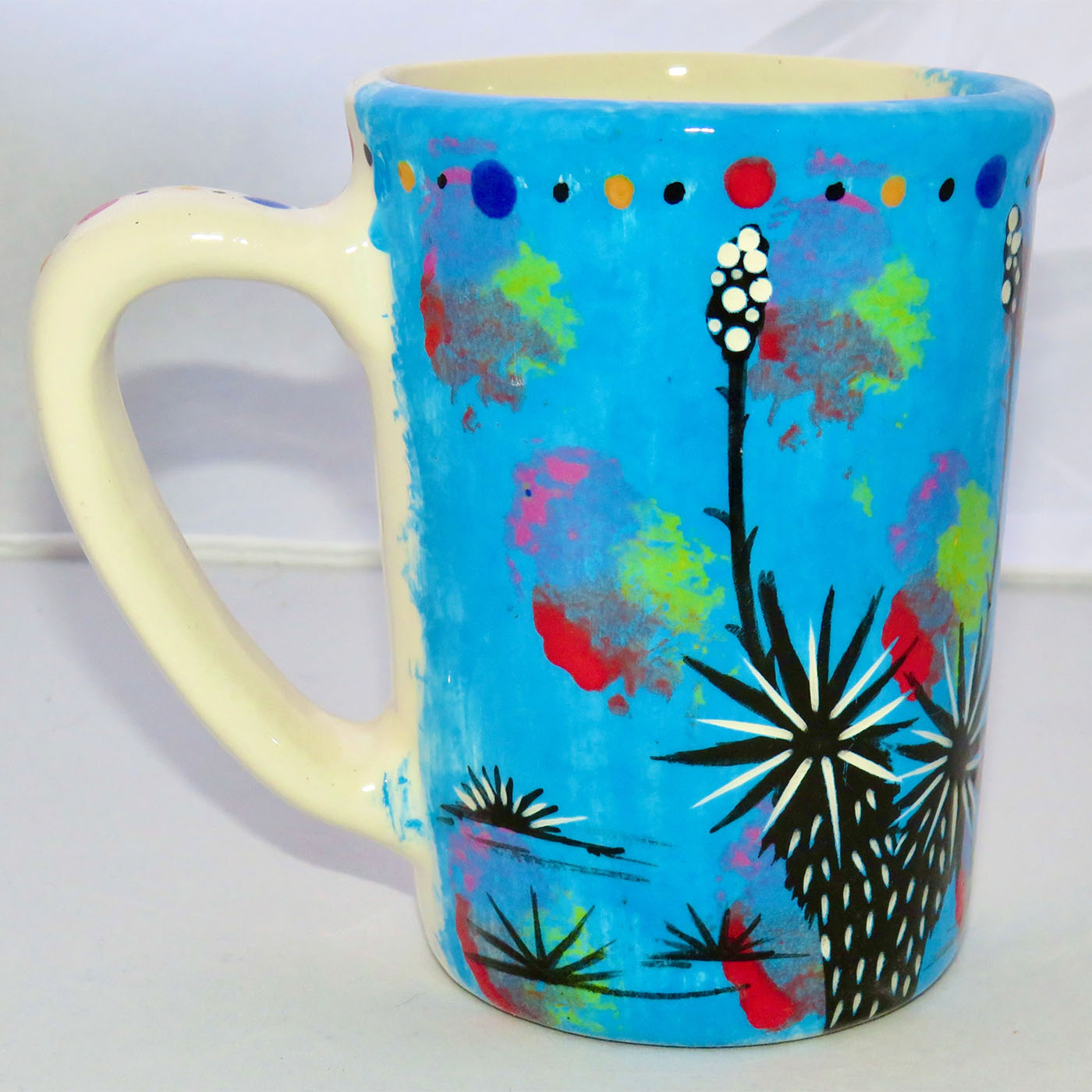 Image of Mana Pottery Large Mug featuring Dancing Peyote Couple on one side and desert vegetation on turquoise blue on reverse.