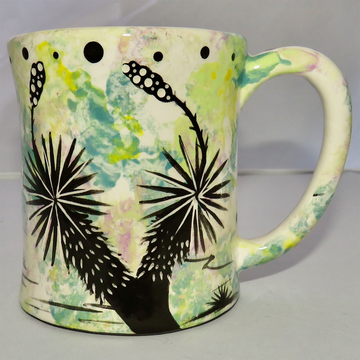 Image of Mana Pottery E-mug featuring armadillo on one side and desert vegetation on the other on a lime background.