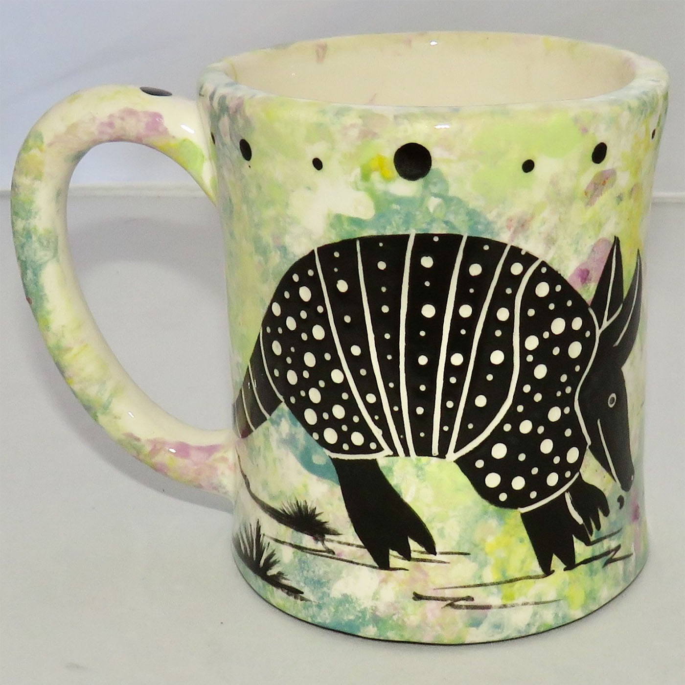 Image of Mana Pottery E-mug featuring armadillo on one side and desert vegetation on the other on a lime background.