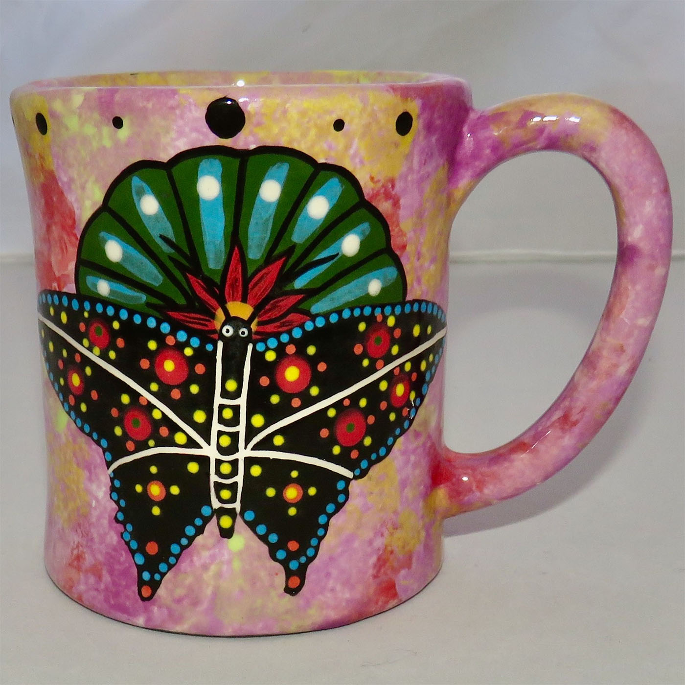 Image of Mana Pottery E-mug featuring butterfly on Peyote on one side and desert vegetation on the other on a purple-yellow background.
