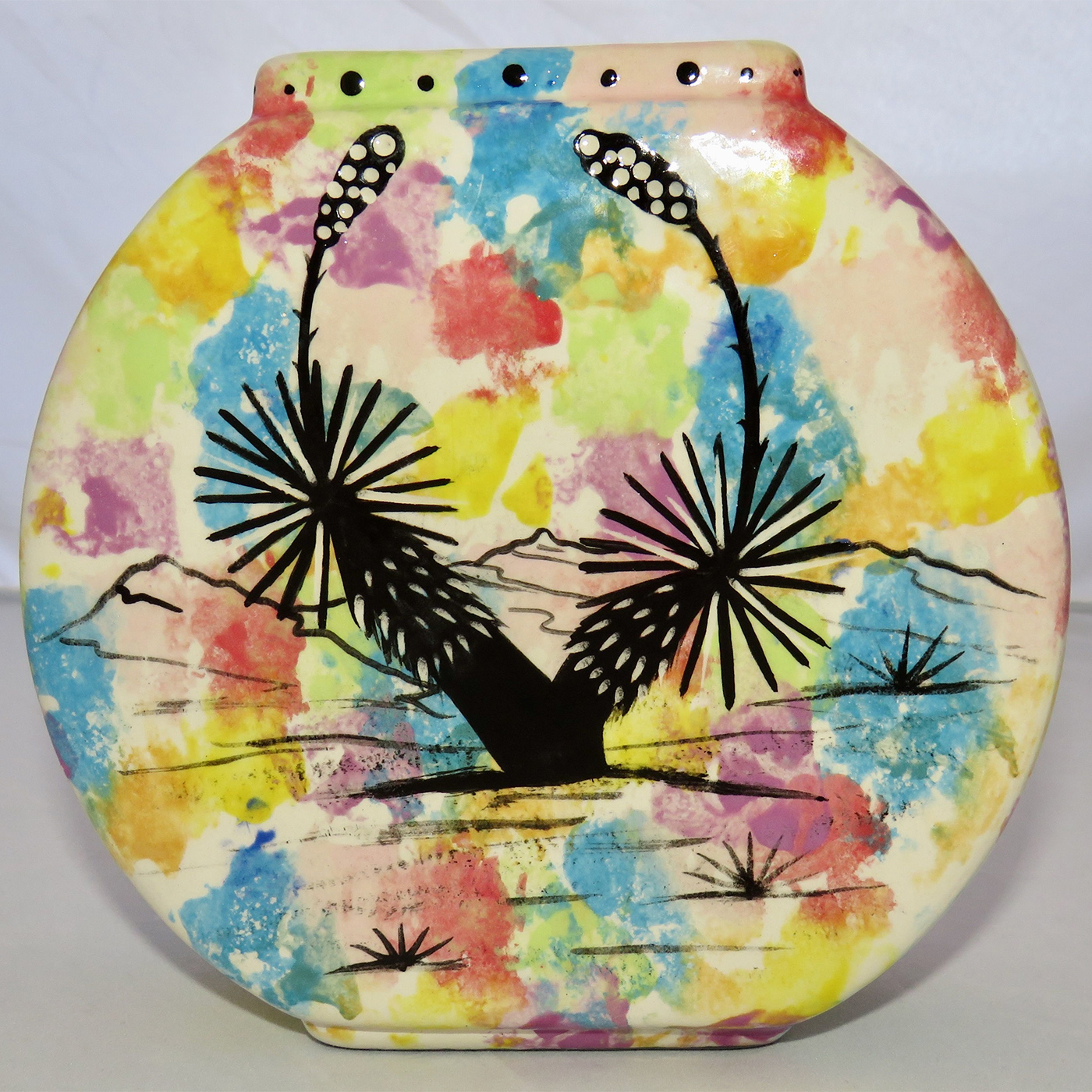 Image of Mana Pottery Pillow Vase featuring deer and desert vegetation on reverse sides, on confetti background.
