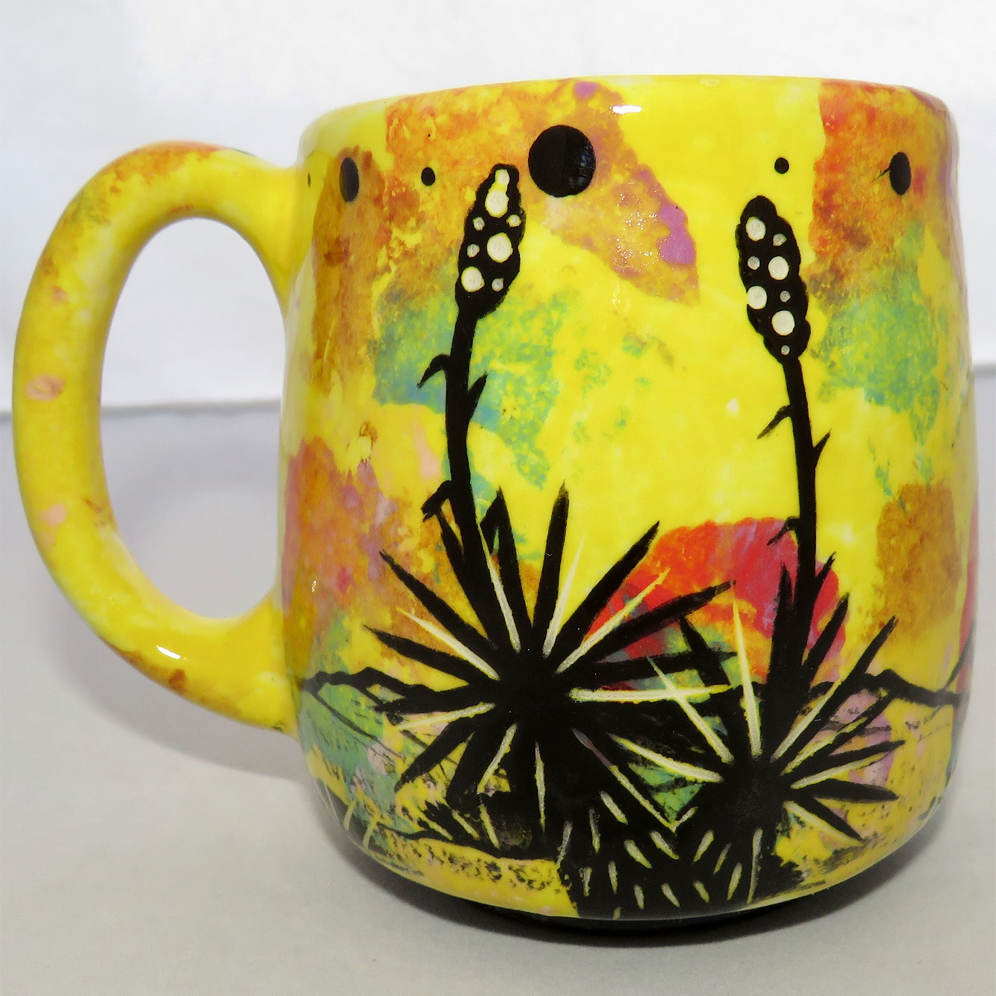 Photo of Mana Pottery Country Cup featuring a charging bull in the desert, on a bright yellow background.