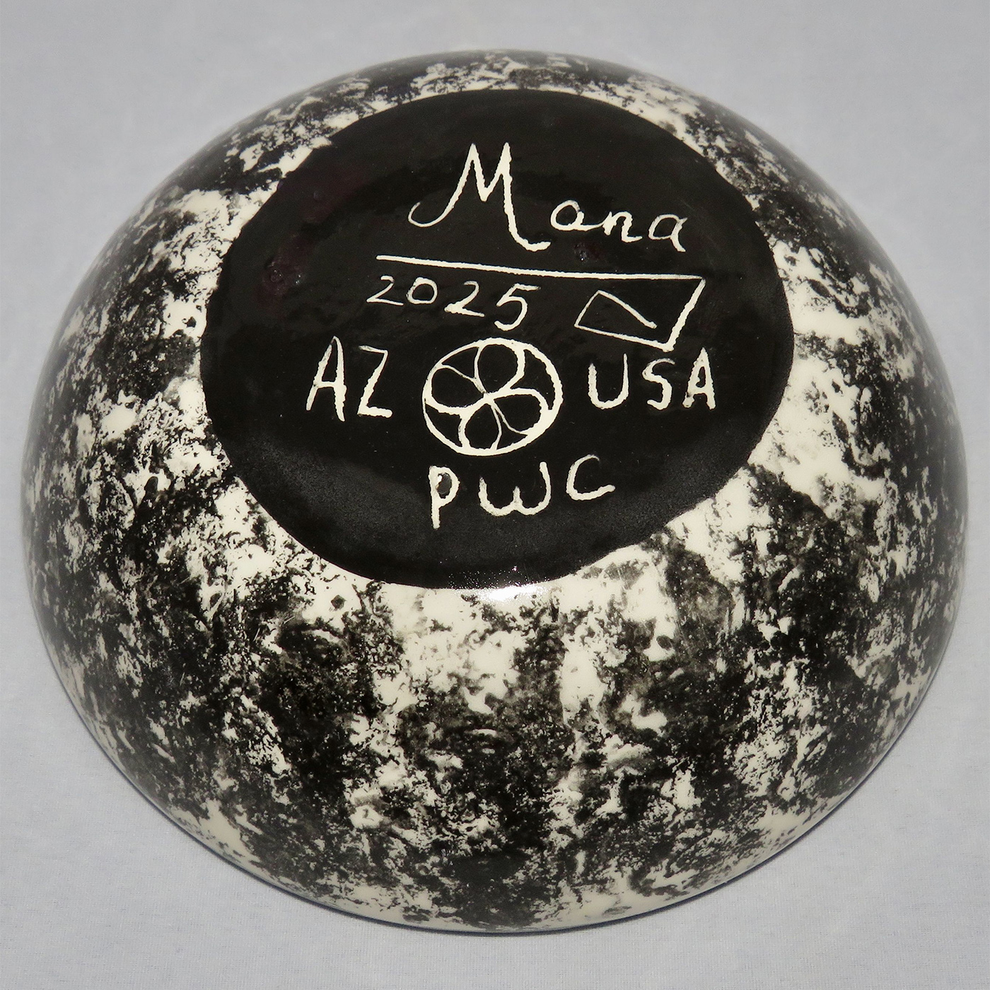Photo of Mana Pottery Five Inch Bowl featuring kitty in desert, on lavender background. This view shows the marbled underside.