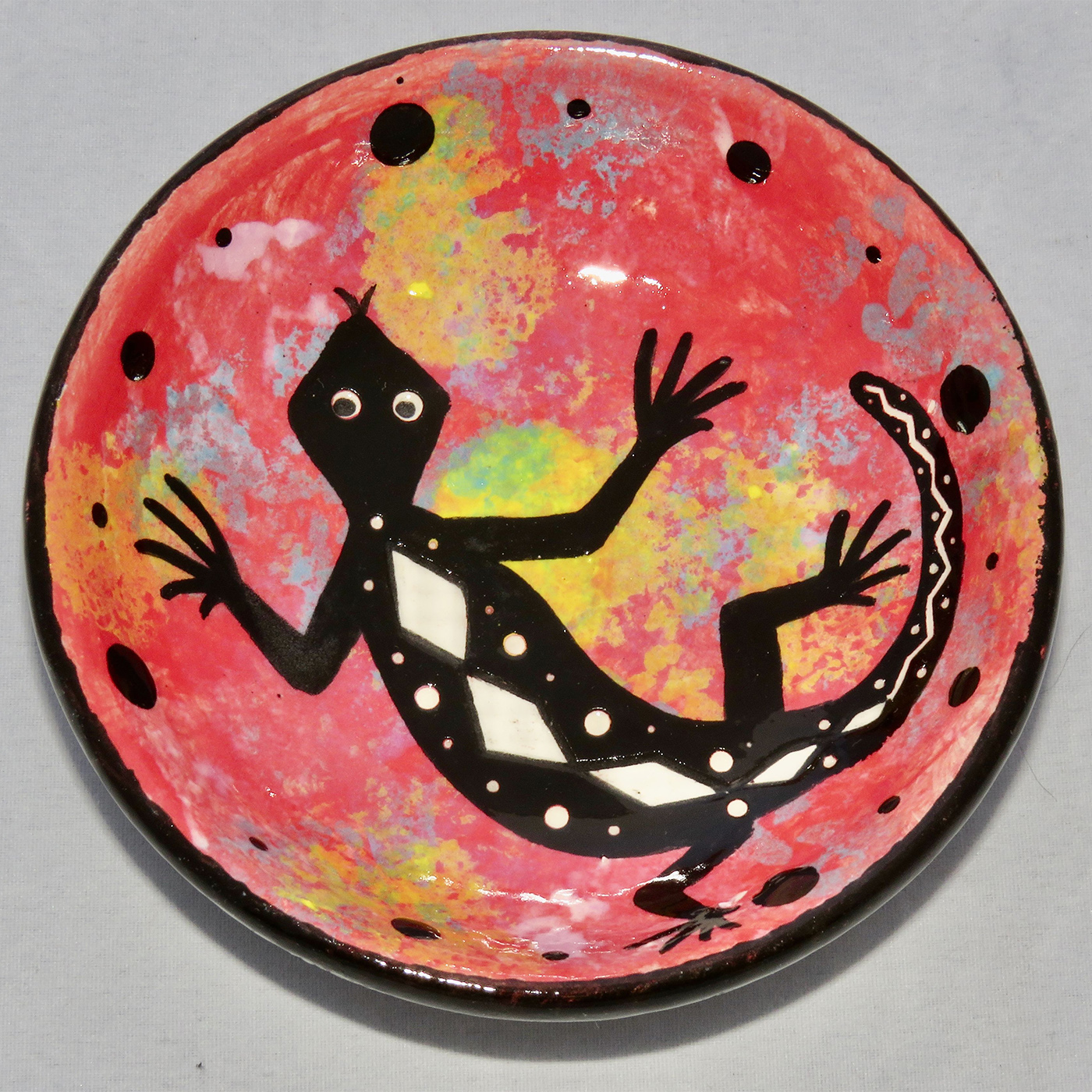 Photo of Mana Pottery Holy Bowl featuring gecko on coral background, and black and white marbled underside.