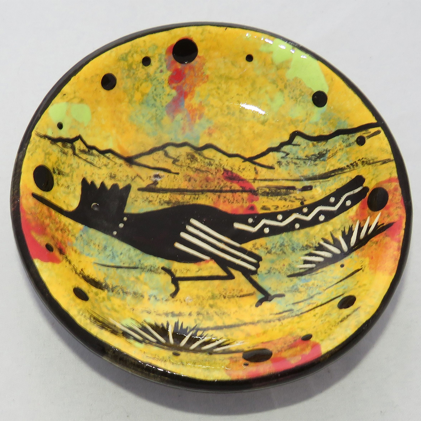 Photo of Mana Pottery Holy Bowl featuring roadrunner on golden yellow background, and black and white marbled underside.