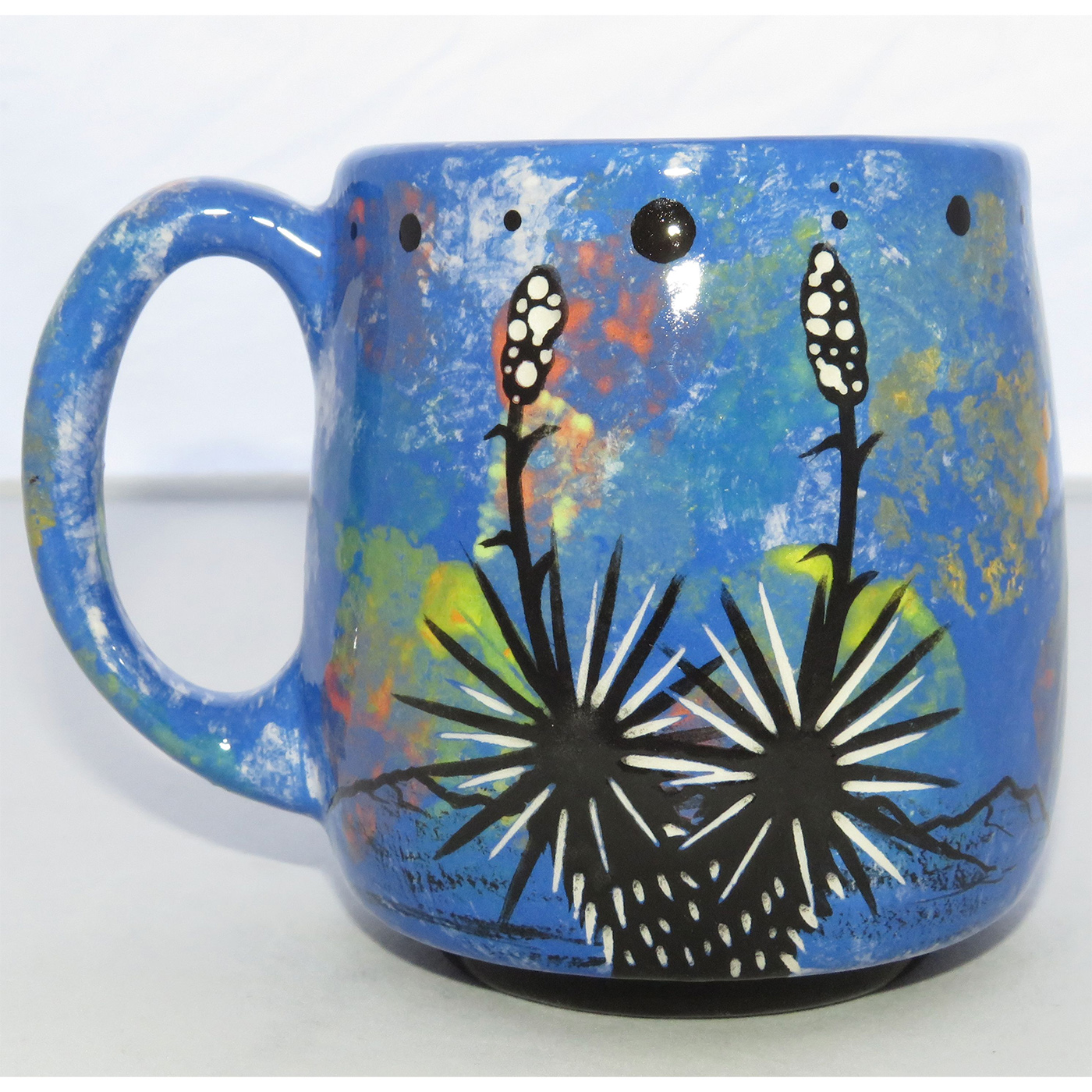Image of Mana Pottery Country Cup featuring dolphin leaping from sea and desert landscape on reverse, all on a background of blue.