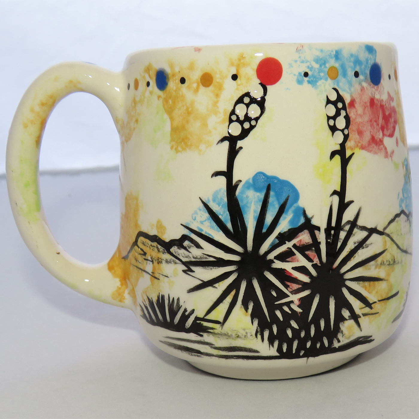 Image of Mana Pottery Country Cup featuring Peyote in bloom and desert landscape on reverse sides, on a confetti-style background.