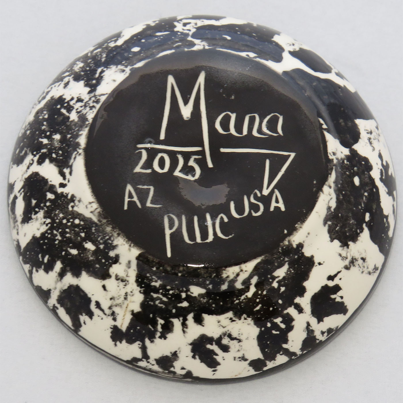 Image of Mana Pottery Holy Bowl featuring horse on on a blue background. This view shows the black and white marbled underside.
