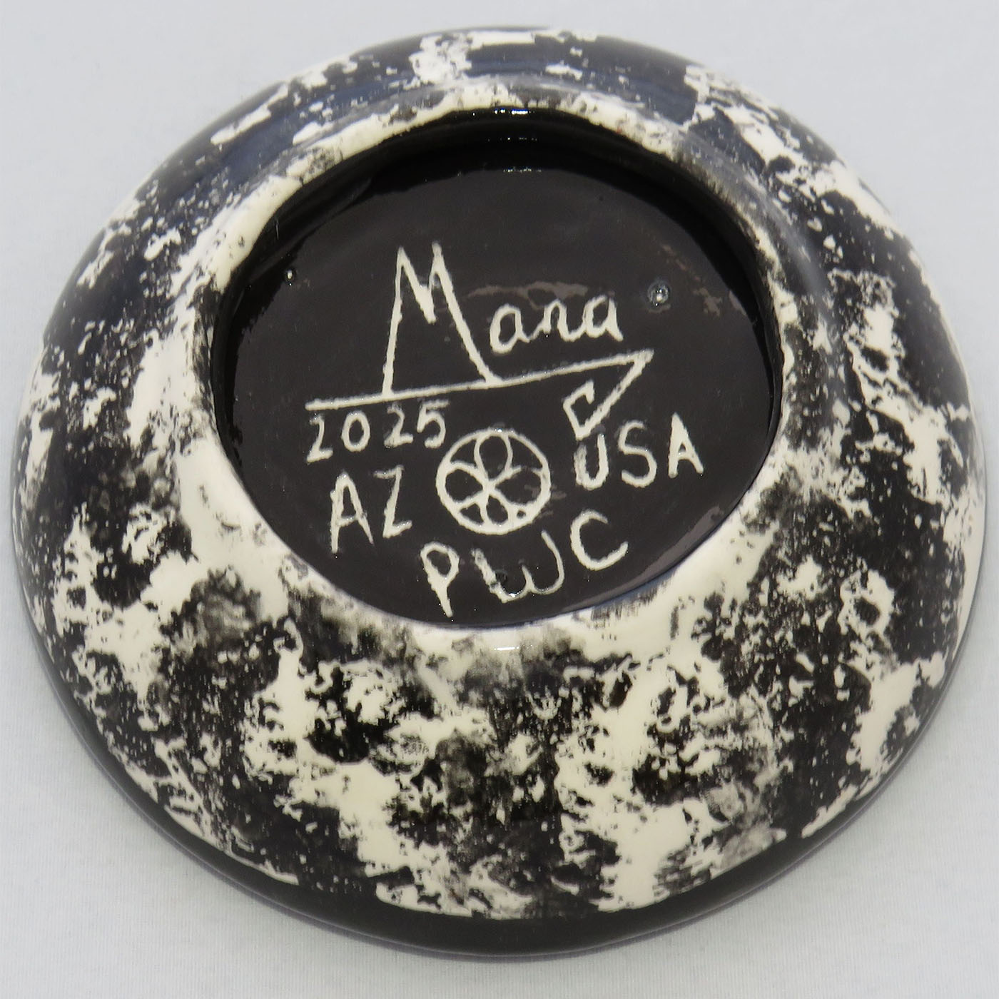 Image of Mana Pottery Holy Bowl featuring deer running in desert, on a chocolate flame background. This view shows the marbled black and white underside.