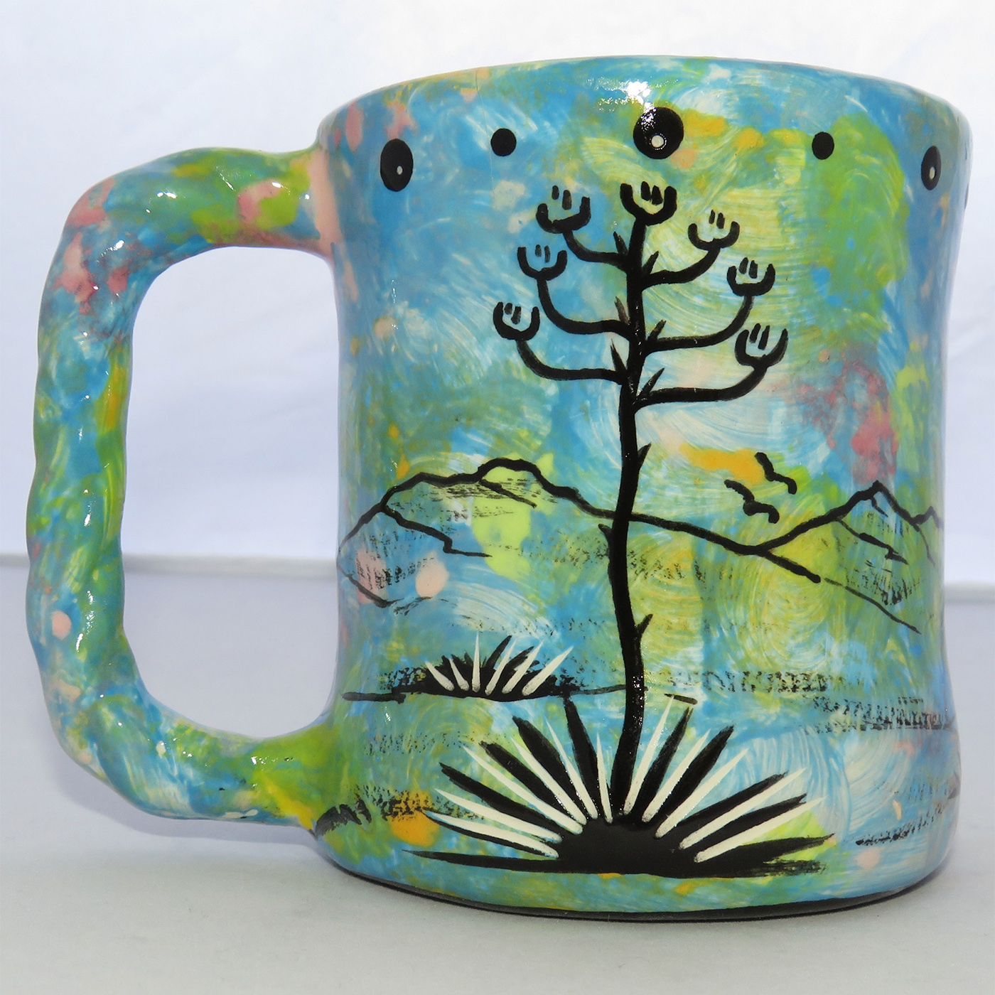 Image of Mana Pottery Rope Mug featuring running deer in desert landscape on a turquoise blue background.