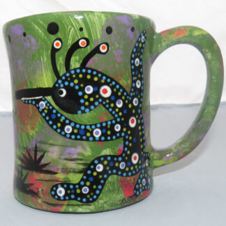 Image of Mana Pottery E-mug featuring a dancing kokopelli on one side and a yucca plant on the reverse, all on a background of a green mix.