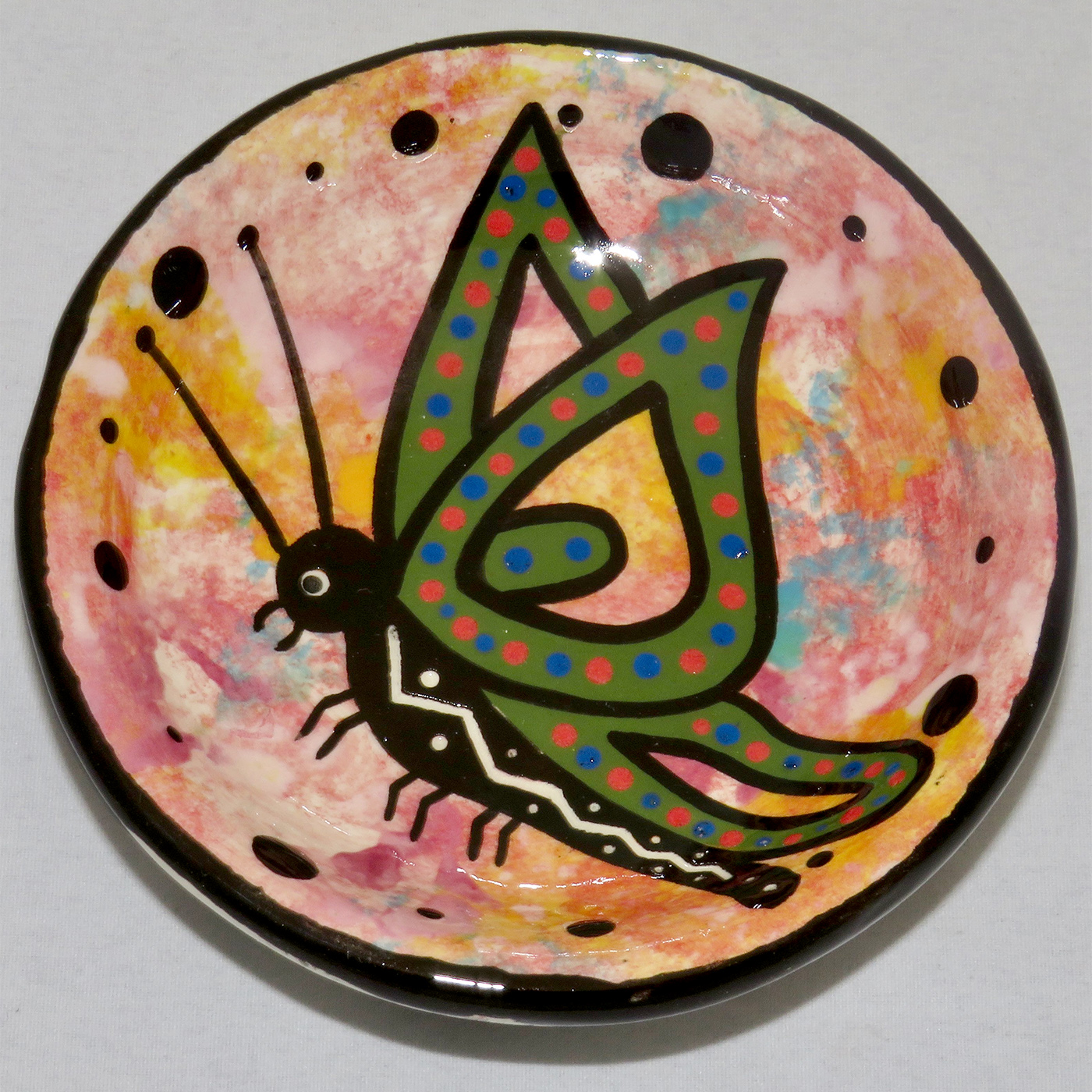 Image of Mana Pottery Holy Bowl featuring butterfly against a rose and gold background. Underside view shows black and white marbled pattern.